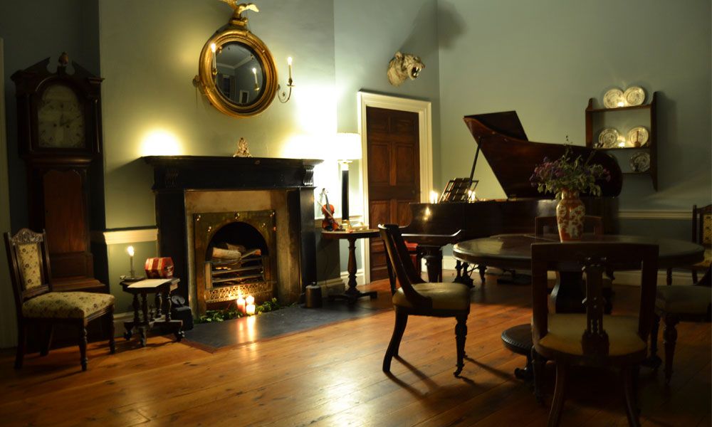 The drawing room at Bellurgan Park lit by firelight and lamps