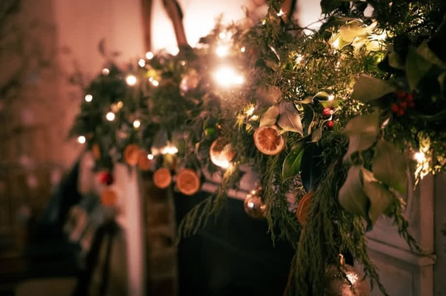 A mantelpiece garland of evergreens, dried orange slices and fairy lights